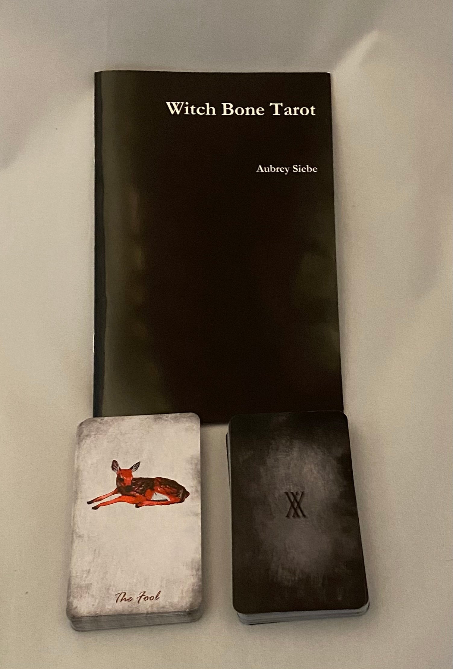 Witch Bone Tarot set with black book, small card, and black box on a white background