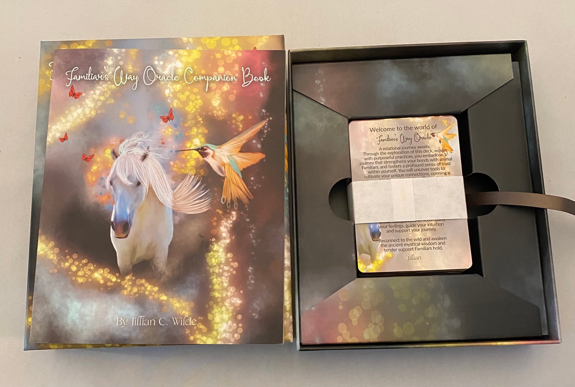 Tarot box with book and card inside featuring a unicorn and hummingbird design on the cover.