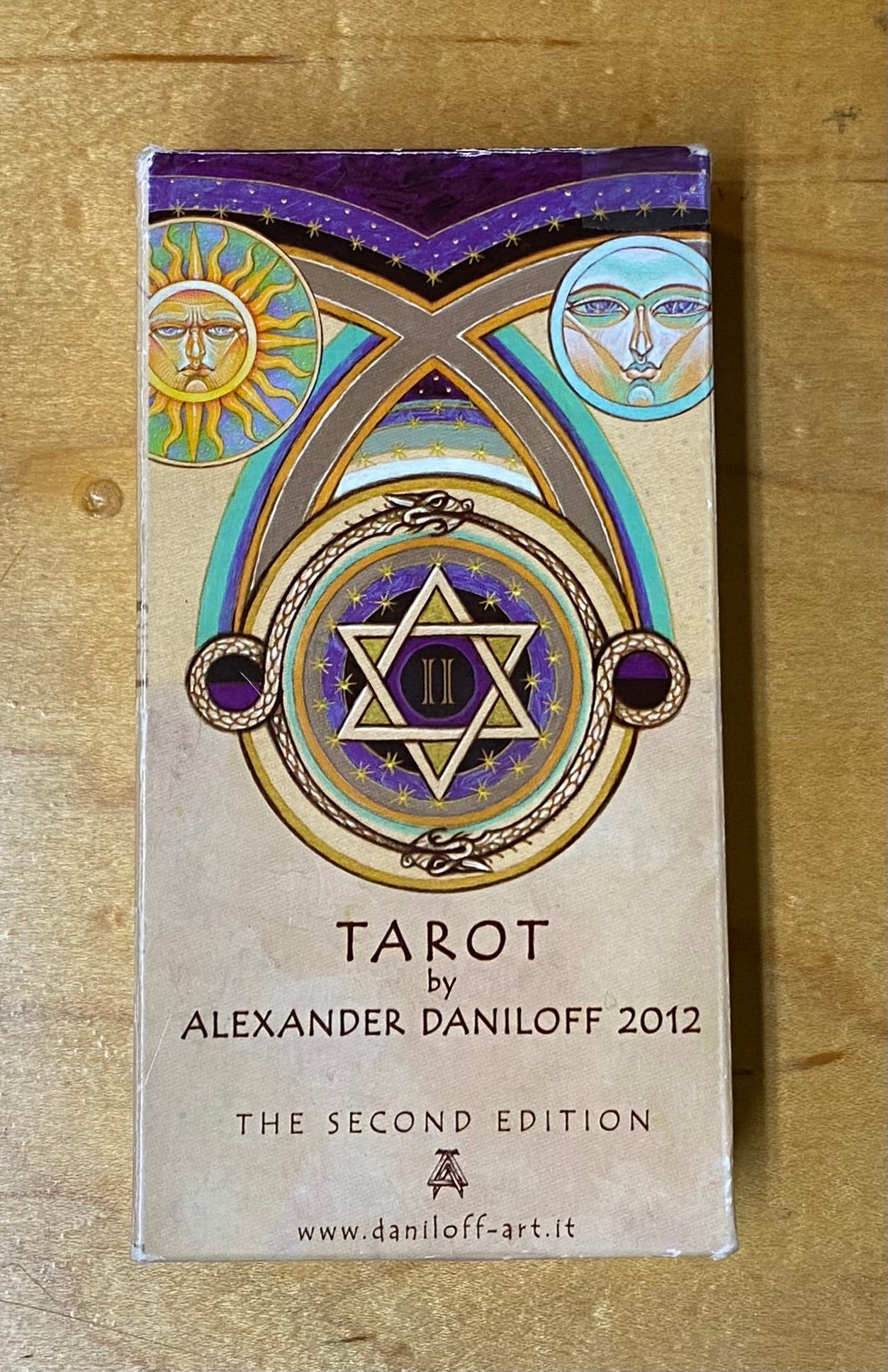 Tarot card packaging with decorative design and text on a wooden surface