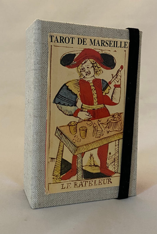 Tarot de Marseille design on the cover, featuring a character in a red hat and coat.