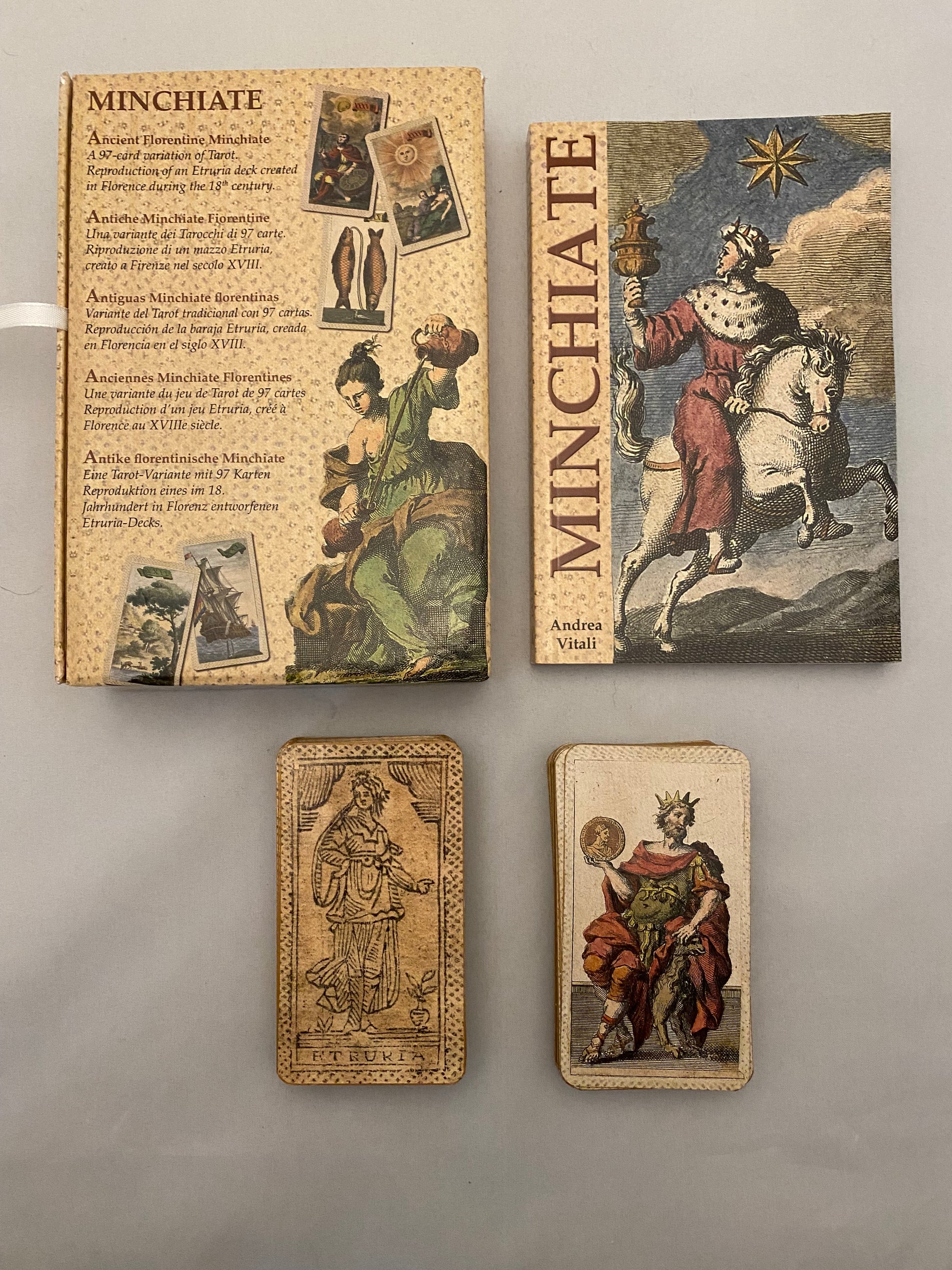 minchiate tarot; Four vintage-style tarot card boxes with intricate designs on a gray background