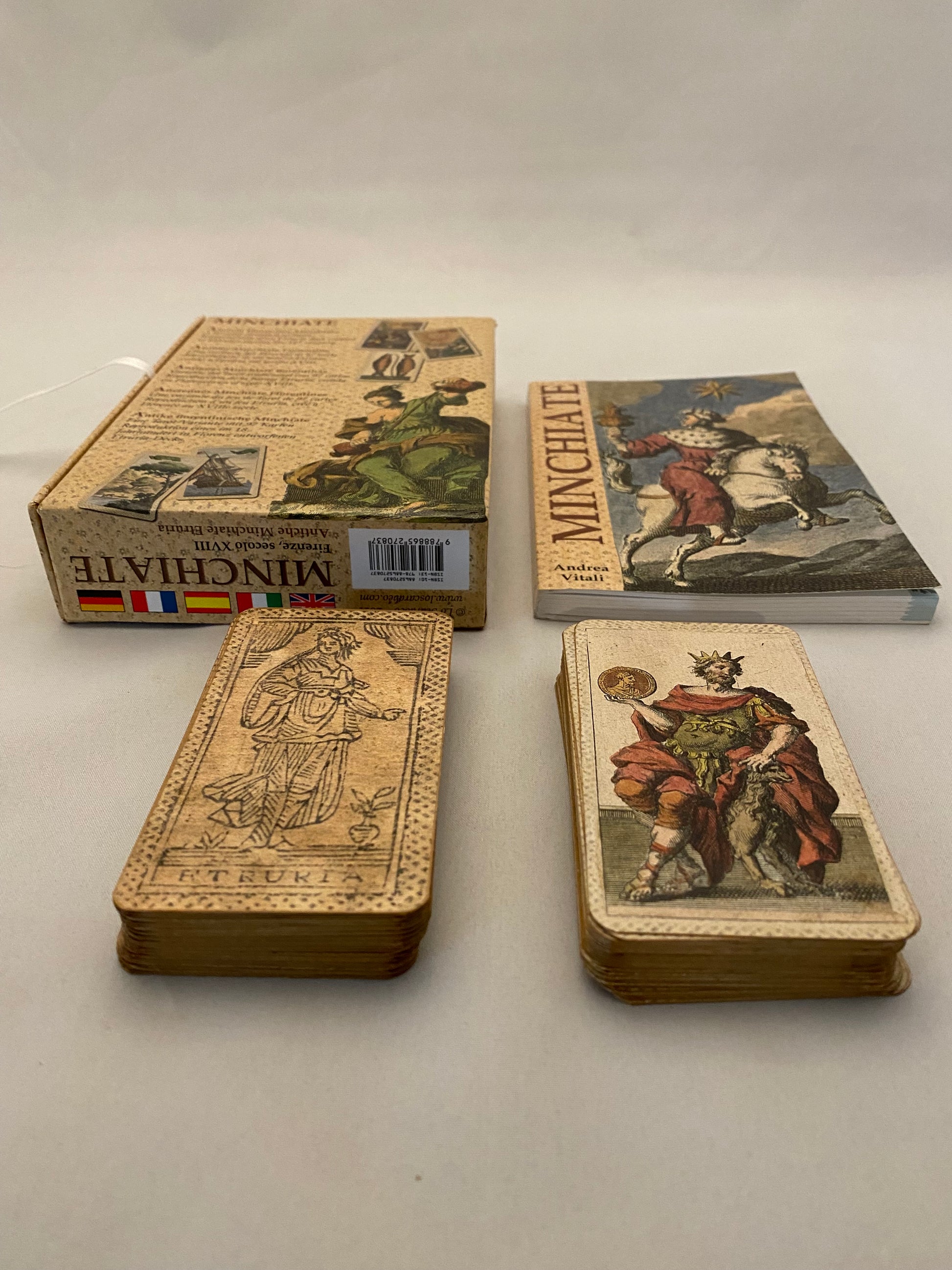 minchiate tarot; Four vintage books with illustrations on a plain wall