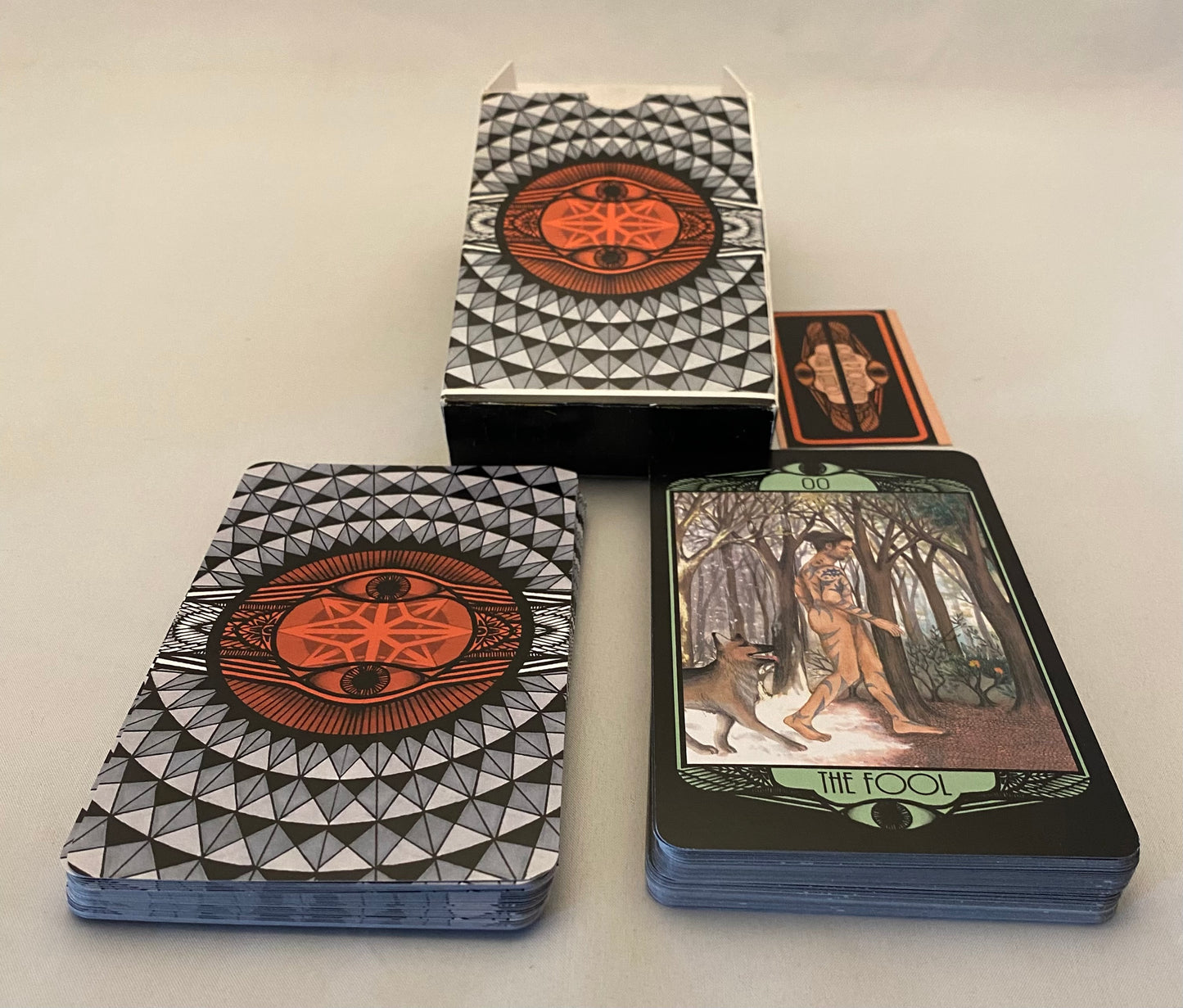 Tarot cards with geometric design on the cover and 'The Fool' card face-up.