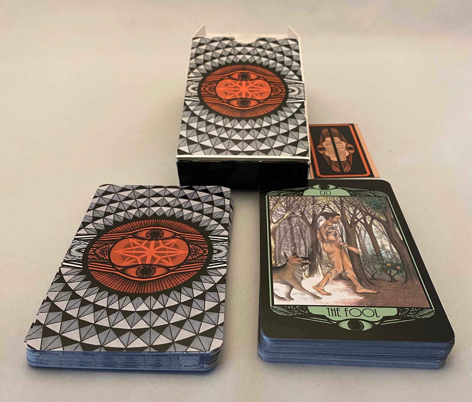 Tarot cards with geometric design on the cover and 'The Fool' card face-up.