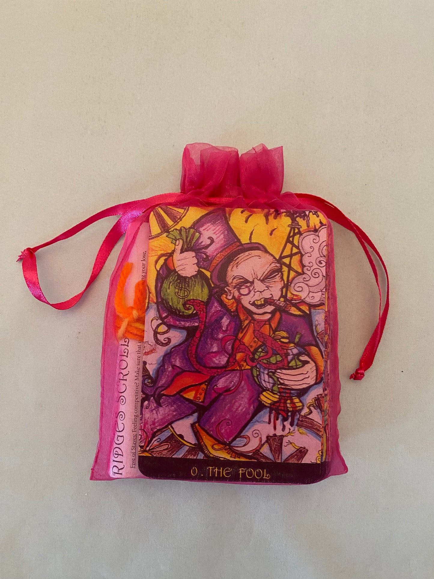 tarot cards in a Decorative pouch with colorful design and pink ribbon on a light background