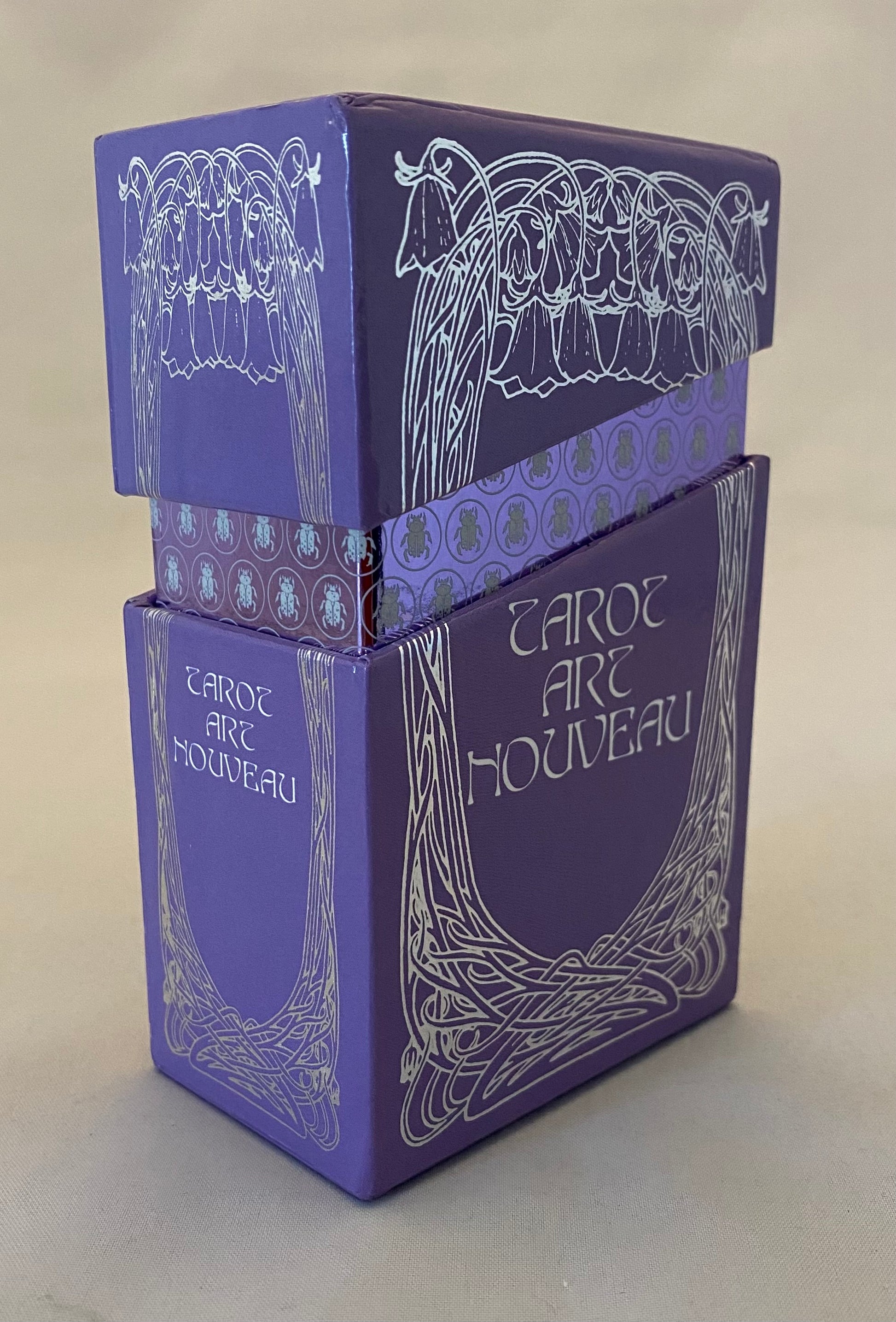 Purple tarot card box with Art Nouveau design on a light gray background