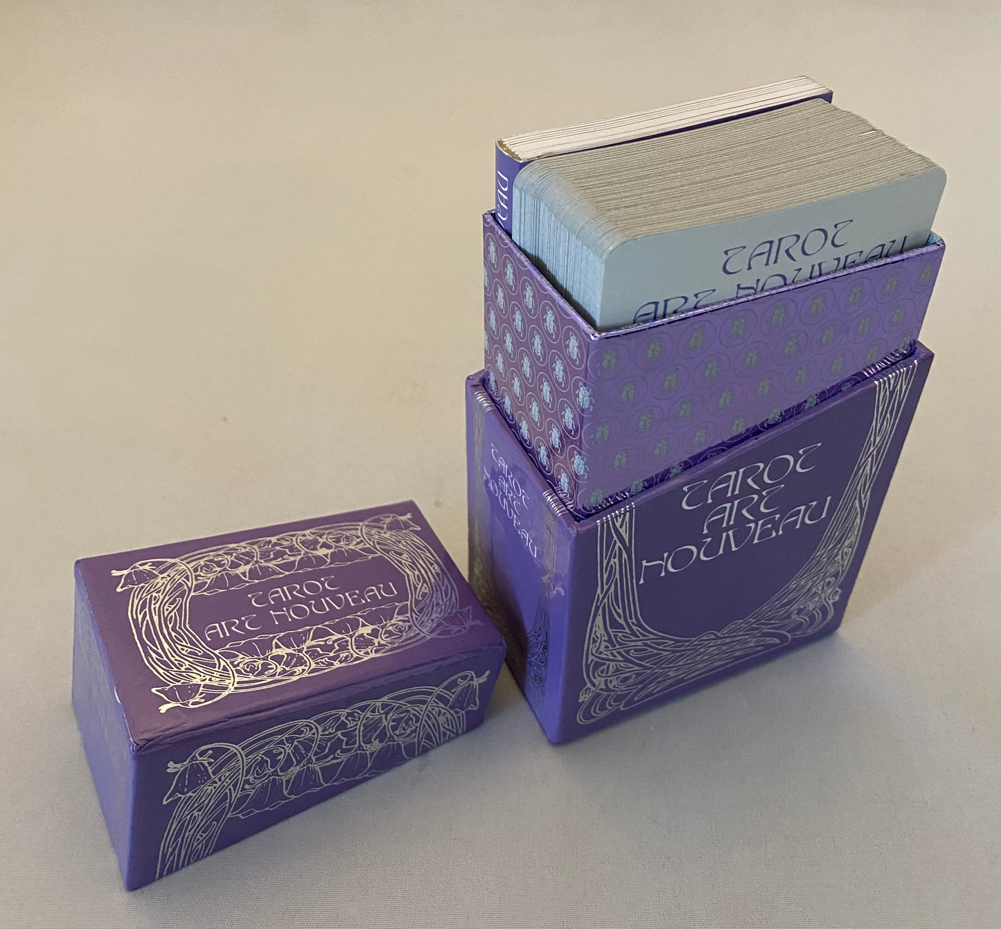 Three decks of Tarot cards in purple boxes on a light gray background