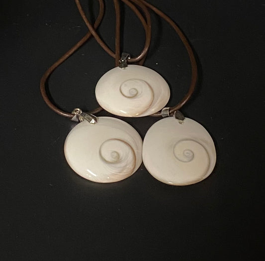 Necklace with three white spiral shell pendants on a dark background