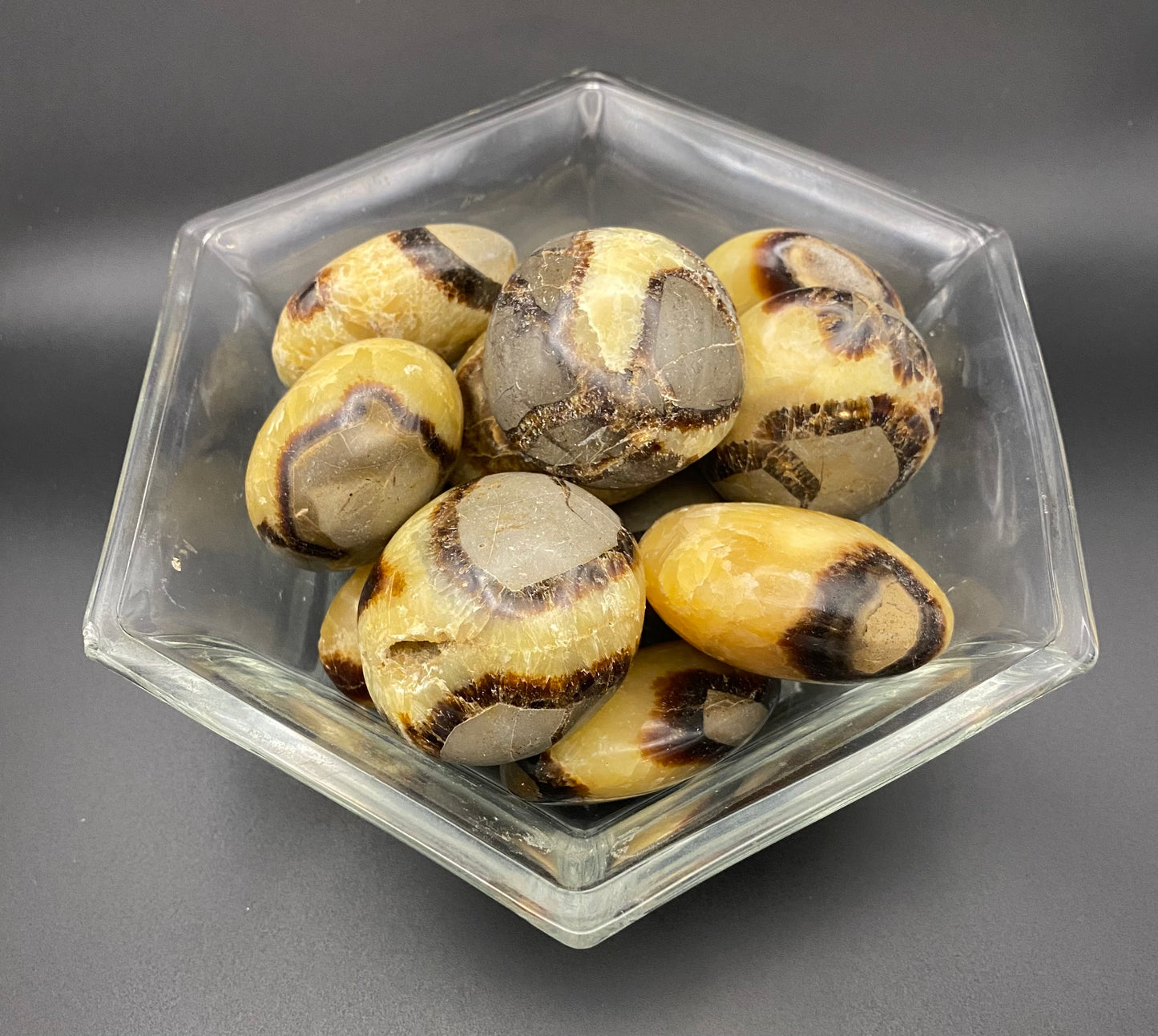 Hexagonal glass bowl filled with Septarian stone on a gray background