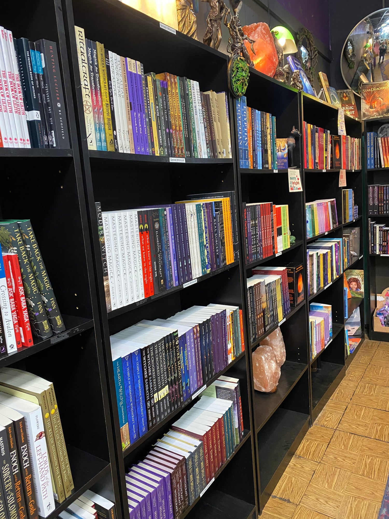 Books on black books shelves with statues and crystals.