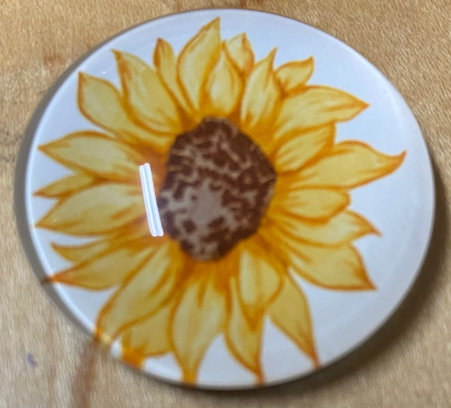 Round magnet with a sunflower design on a wooden surface