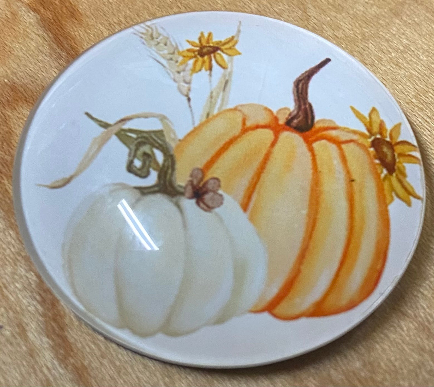 Round magnet with pumpkins and sunflowers on a wooden surface