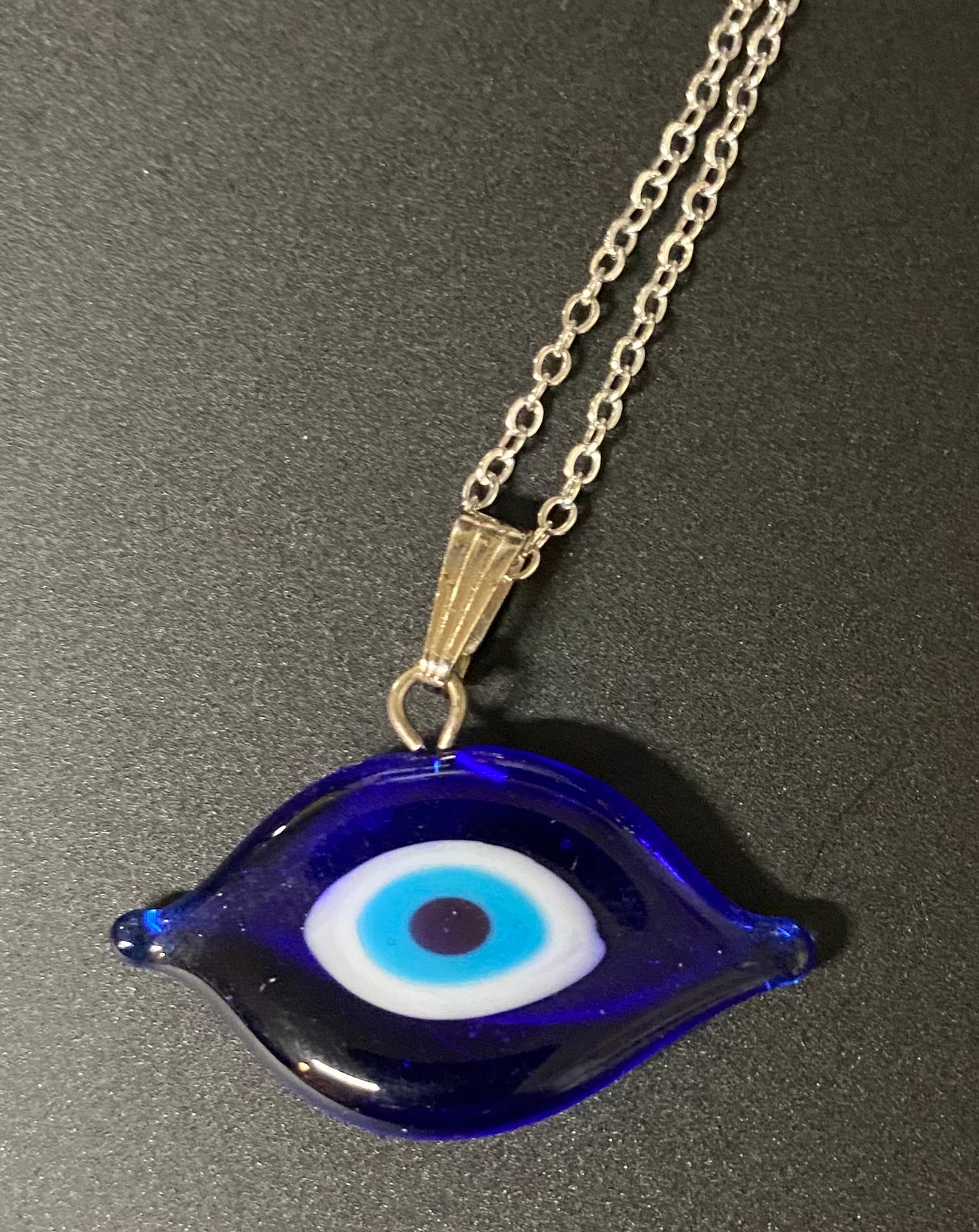 Blue eye-shaped pendant on a chain against a dark background