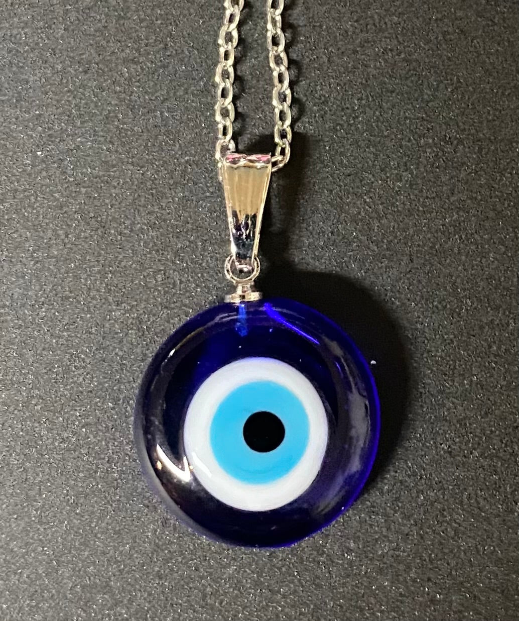 Blue evil eye pendant necklace on a gray background