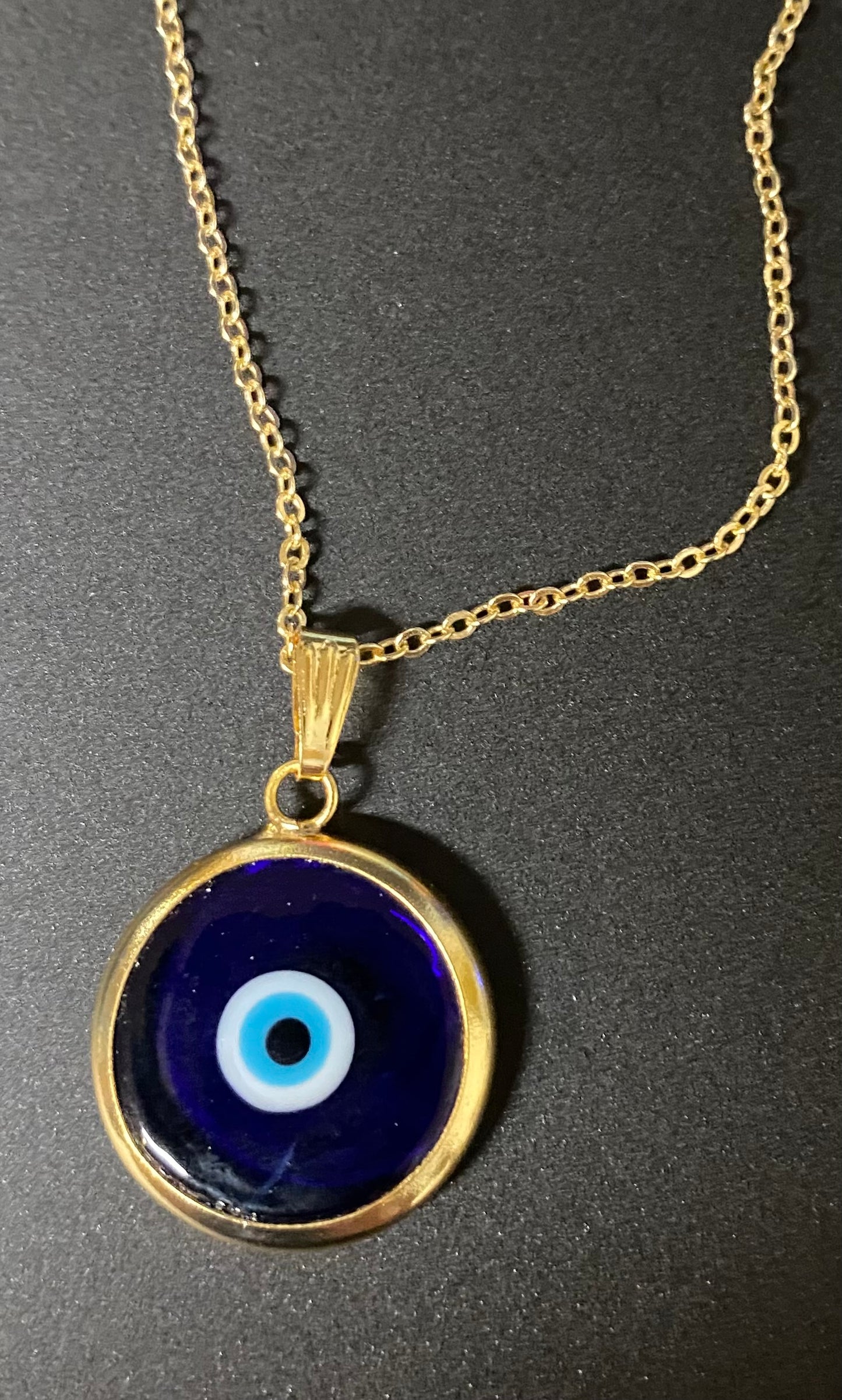 Necklace with a blue evil eye pendant on a dark background