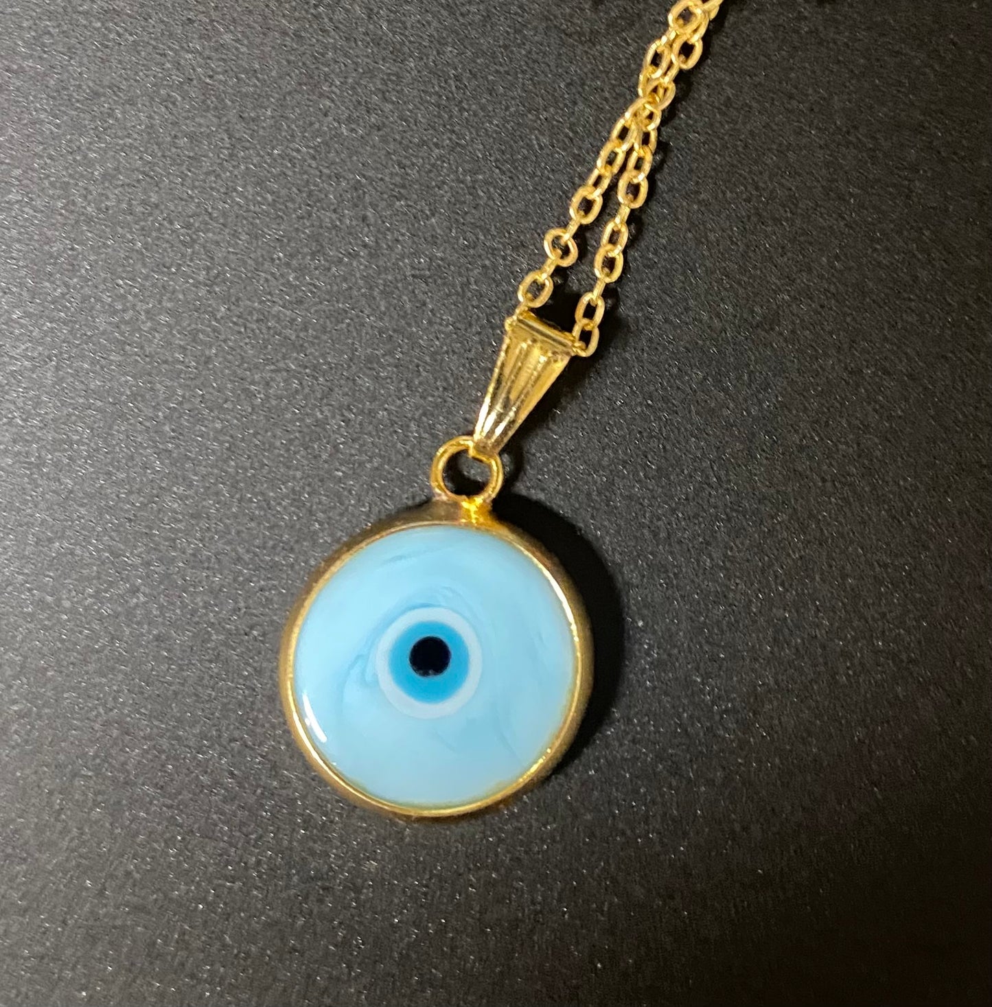 Necklace with a blue evil eye pendant on a black background