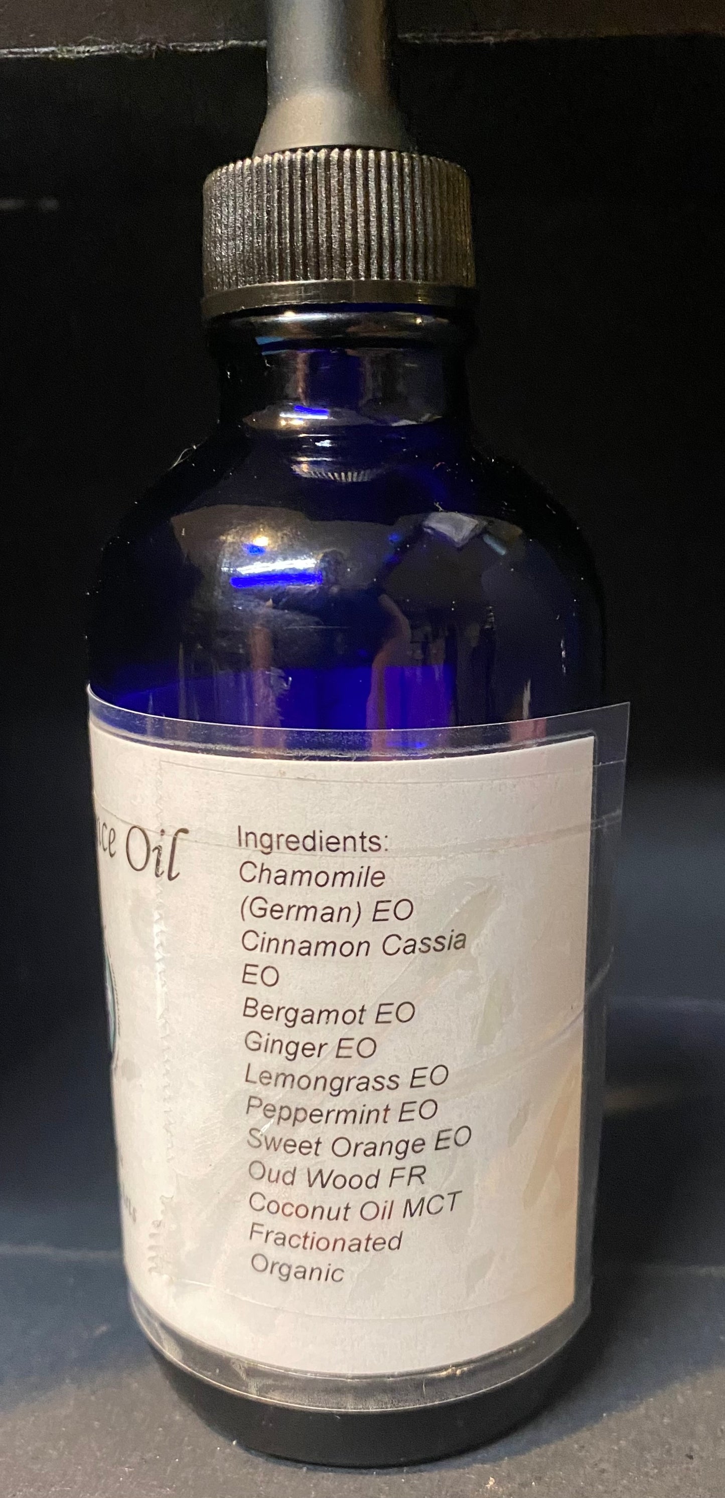 Blue glass bottle with dropper labeled 'Essential Oil' on a dark background