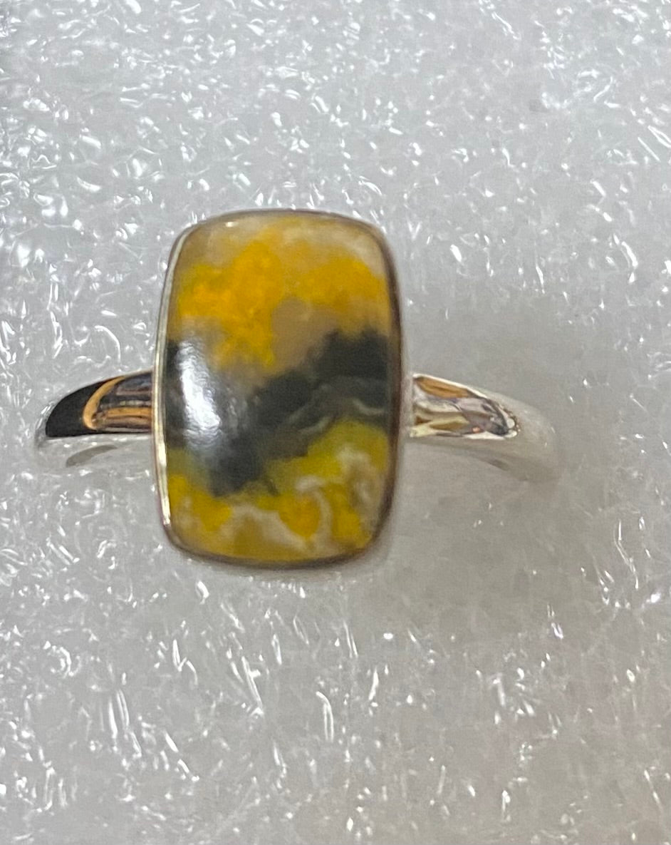 Ring with a yellow and black marbled stone on a textured white background