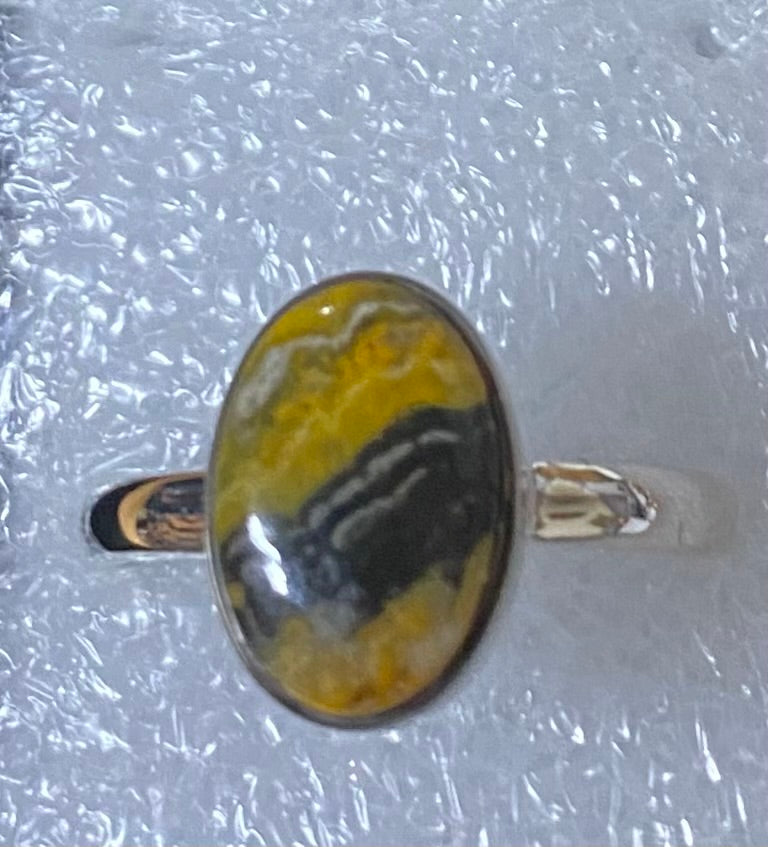 Ring with a yellow and black marbled stone on a textured gray background