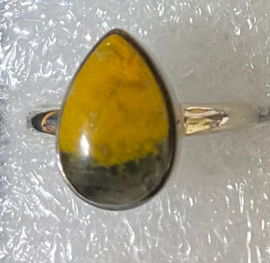 Ring with a yellow teardrop-shaped stone on a textured white background
