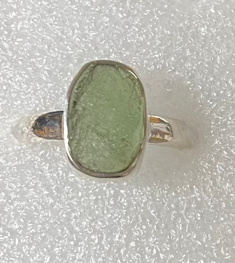 Green ring with silver band on a textured white background