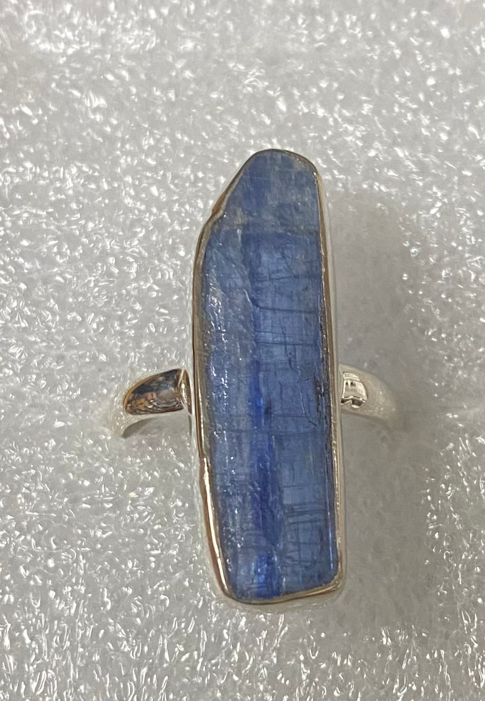 Silver ring with a blue stone on a textured gray background