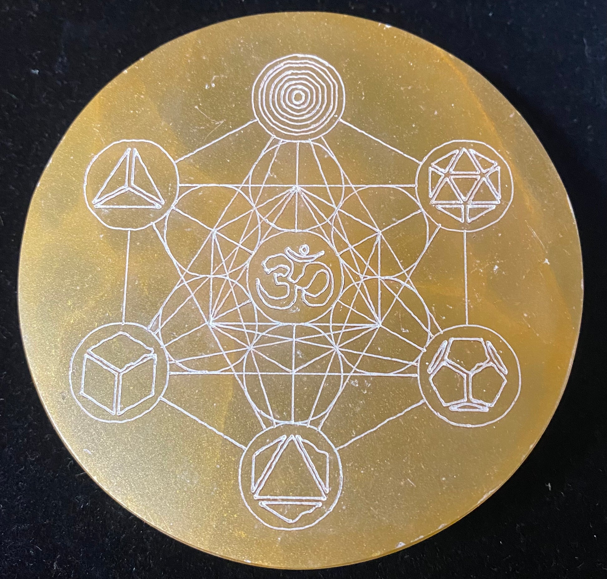 Circular object with white geometric line art on a dark background