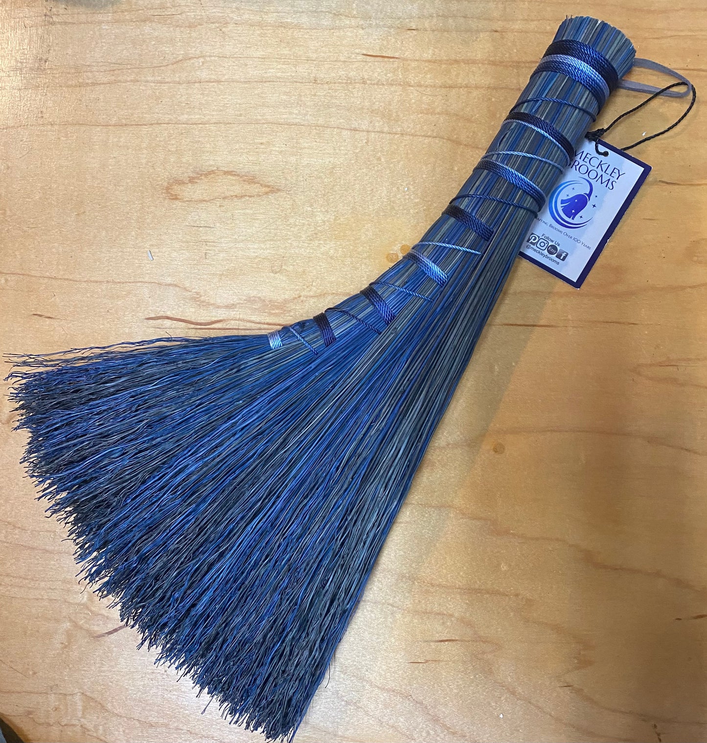 Blue broom with a tag on a wooden surface