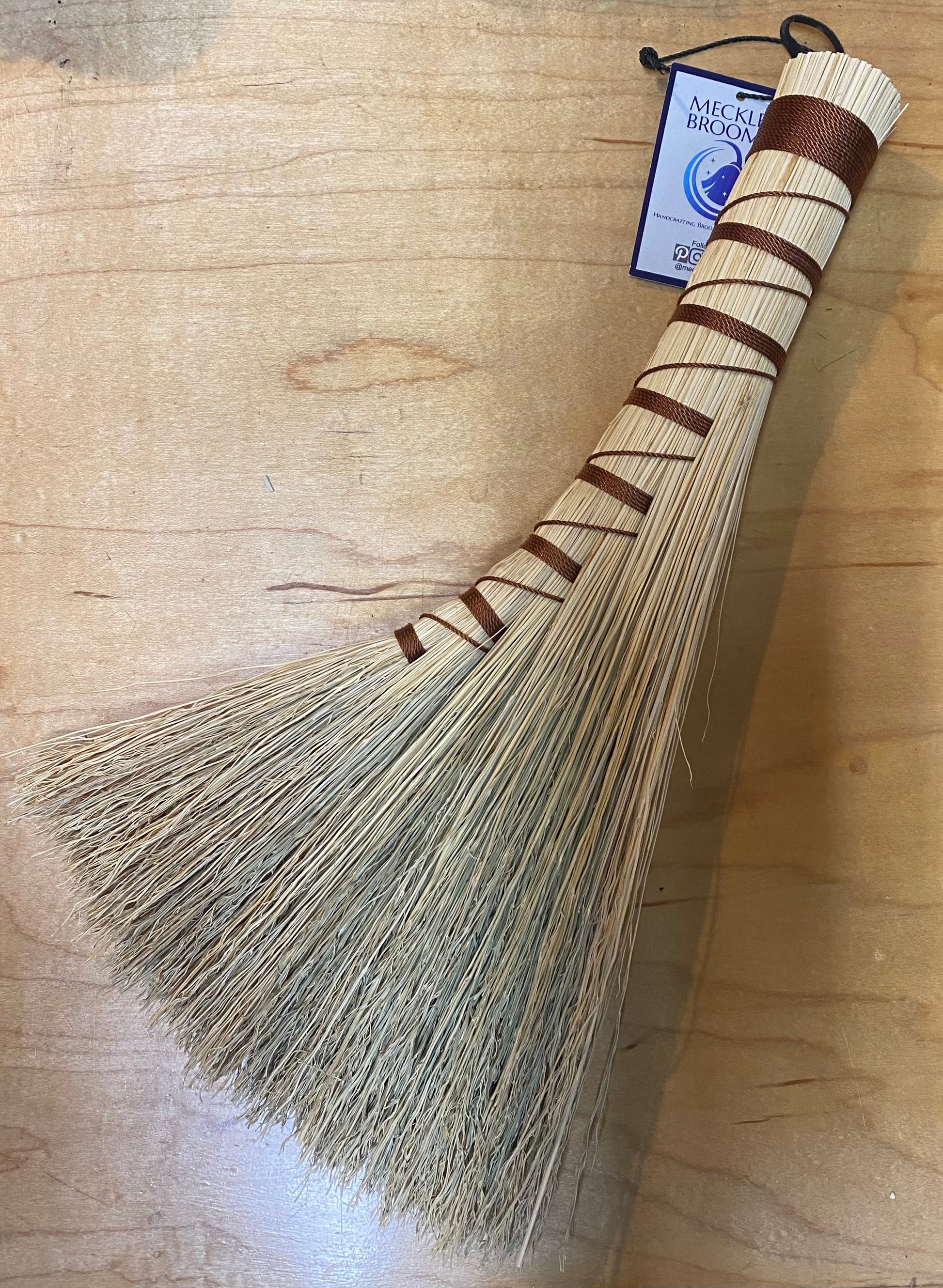 Handmade broom with a wooden handle on a wooden surface
