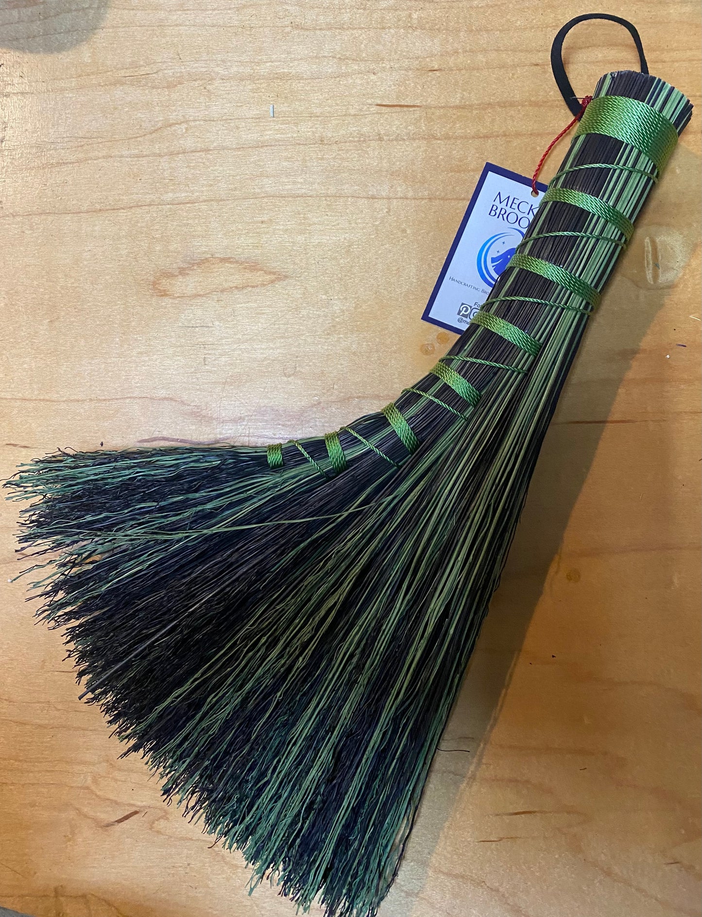 Green broom with a label on a wooden surface