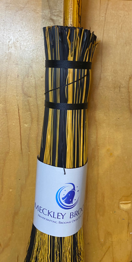 Broom with black bristles and a Meckley Brooms  label on a wooden background