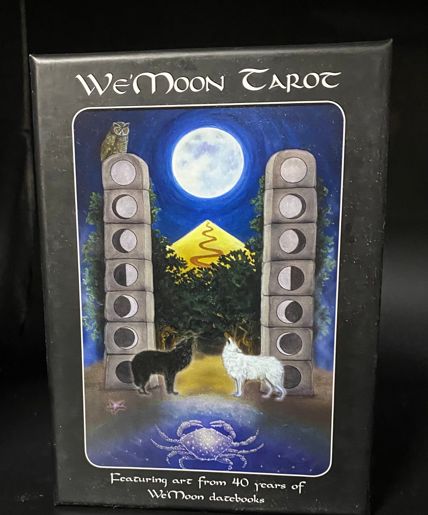 We'Moon Tarot card box with artwork of two wolves and a moon phase cycle.
