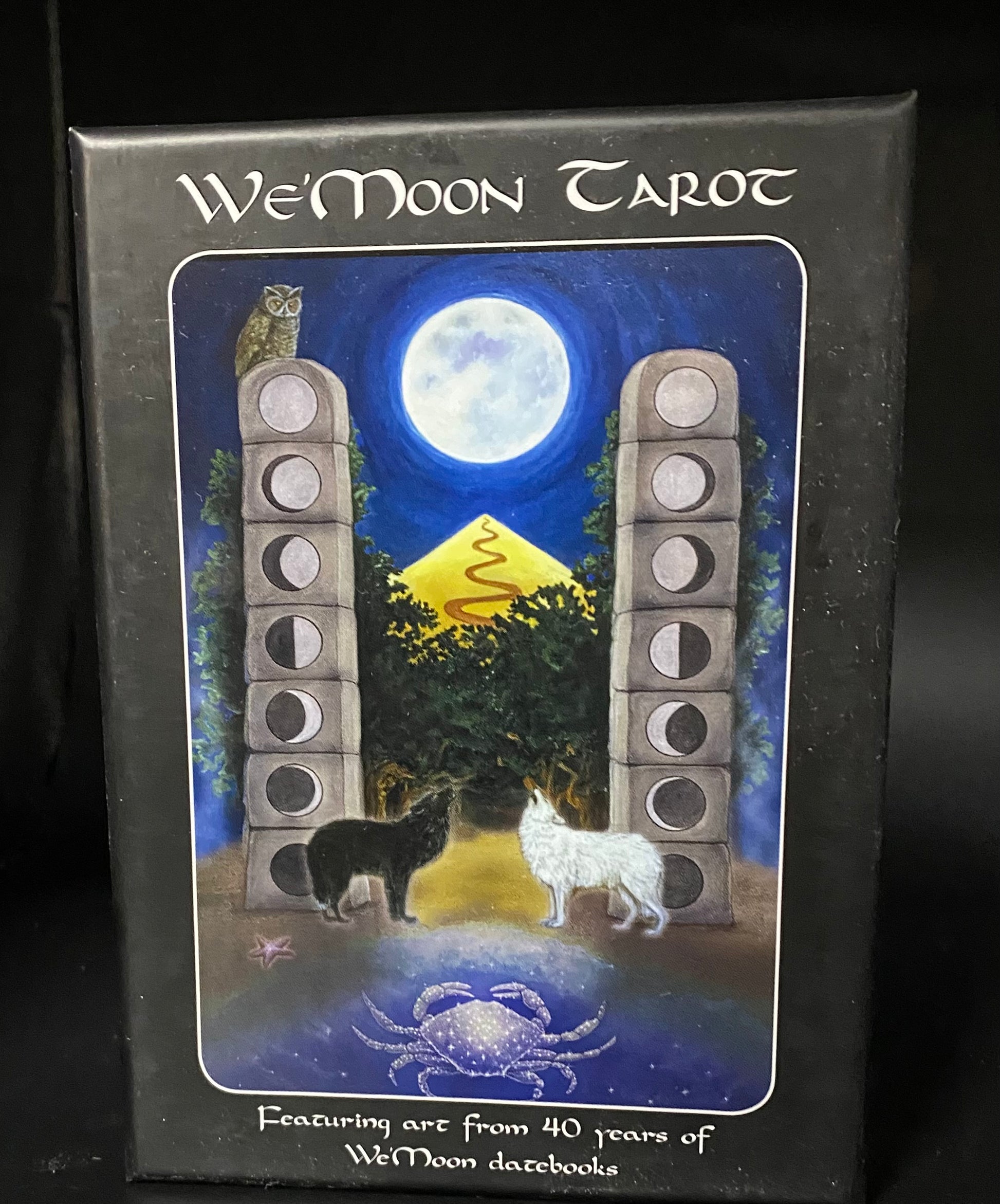 We'Moon Tarot card box with artwork of two wolves and a moon phase cycle.