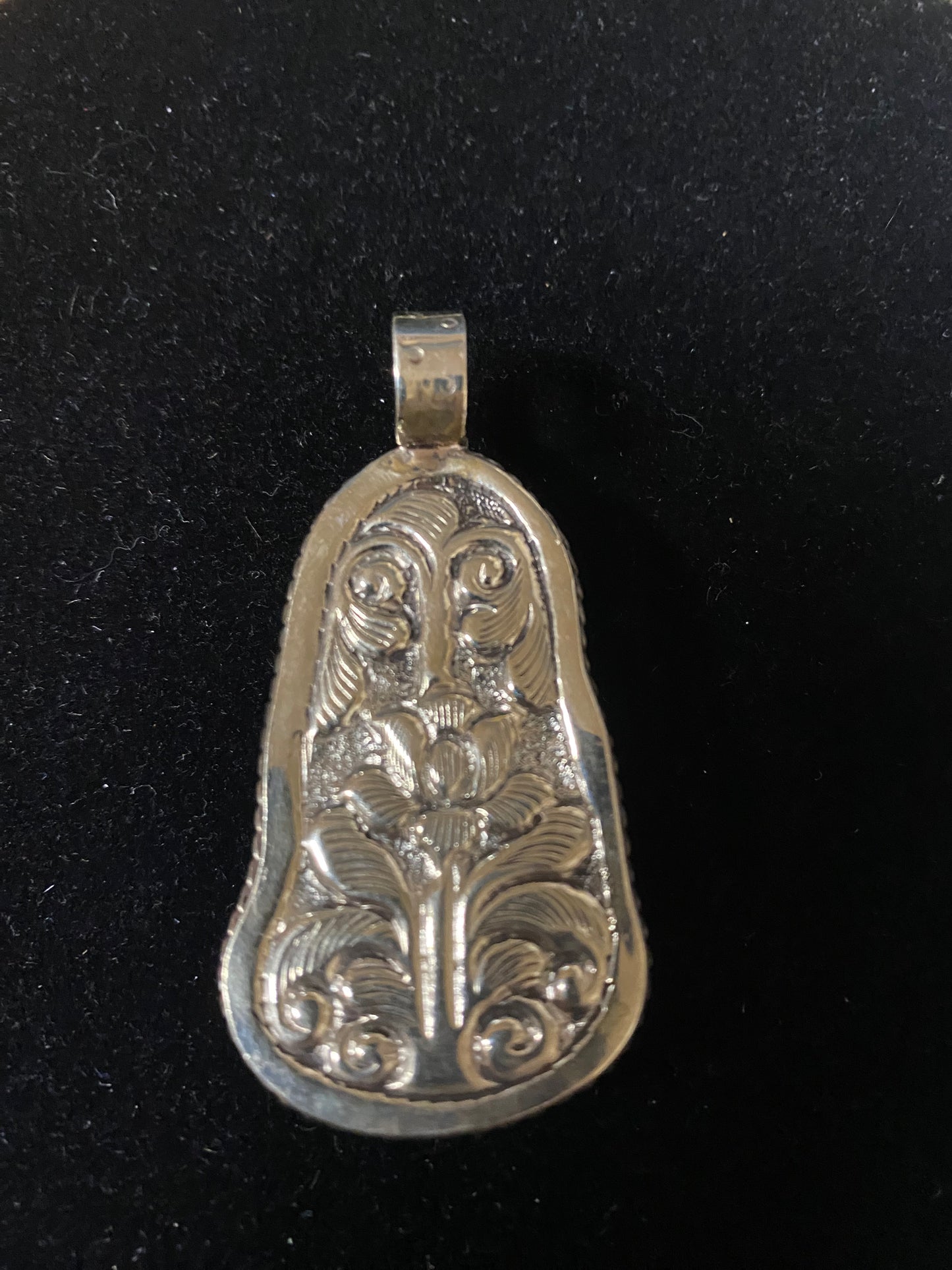 Decorative silver pendant on a black background