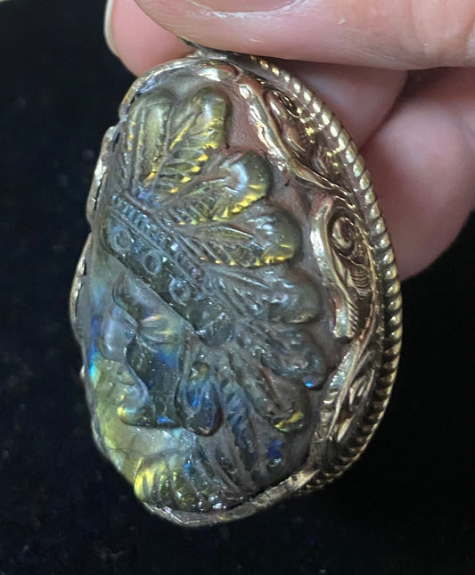 Decorative stone with leaf patterns held by a hand against a dark background
