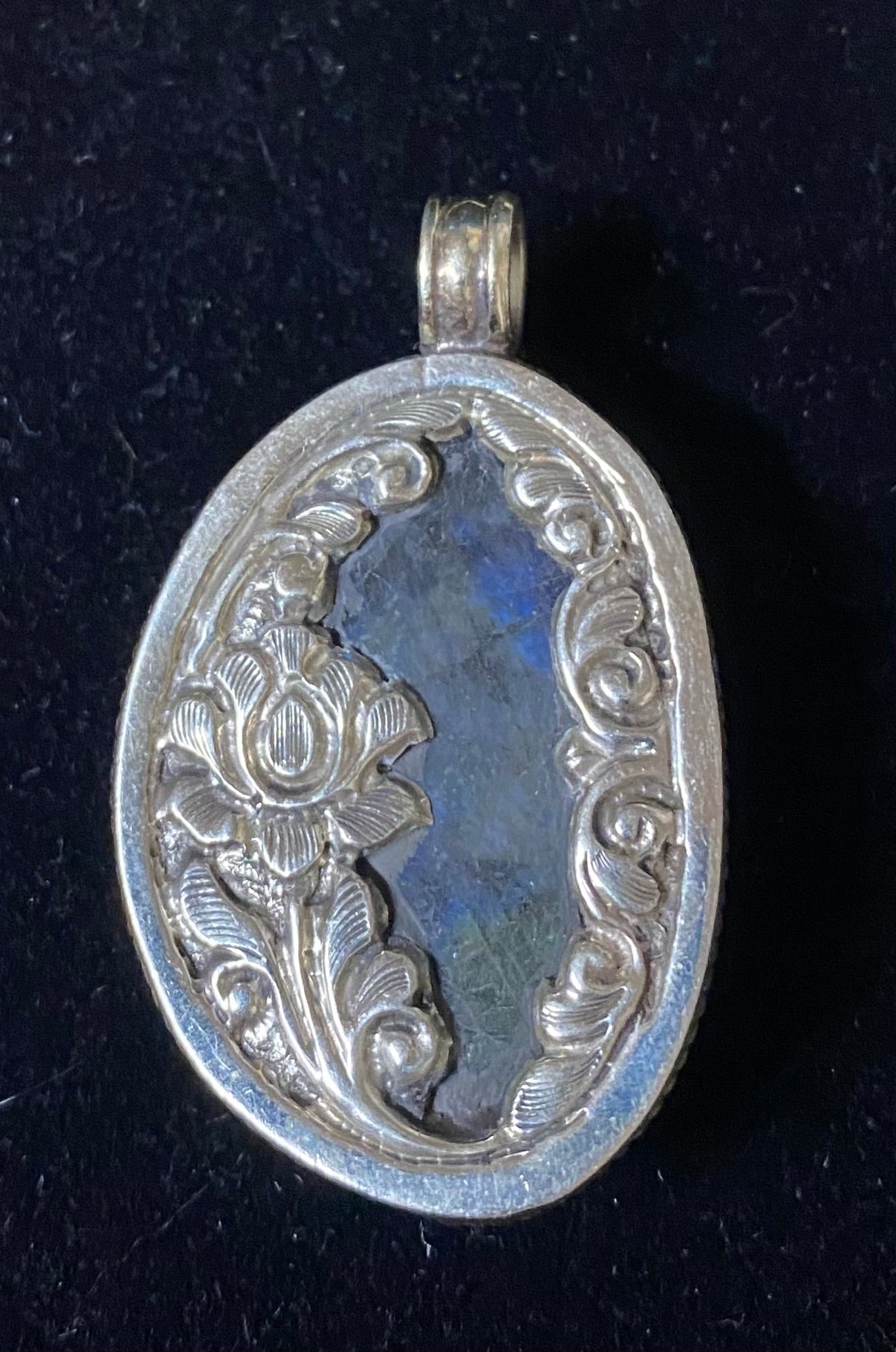 Silver pendant with intricate designs on a black background