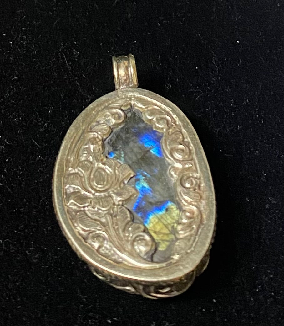 Silver pendant with a rainbow-colored stone on a black background