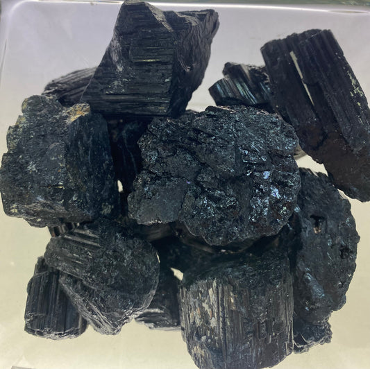 Collection of dark-colored mineral crystals on a reflective surface