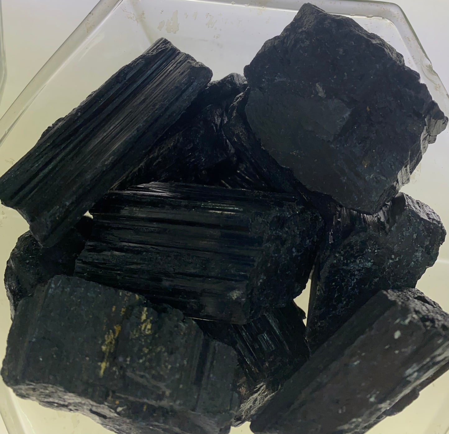 Stack of dark-colored rocks or crystals on a clear surface