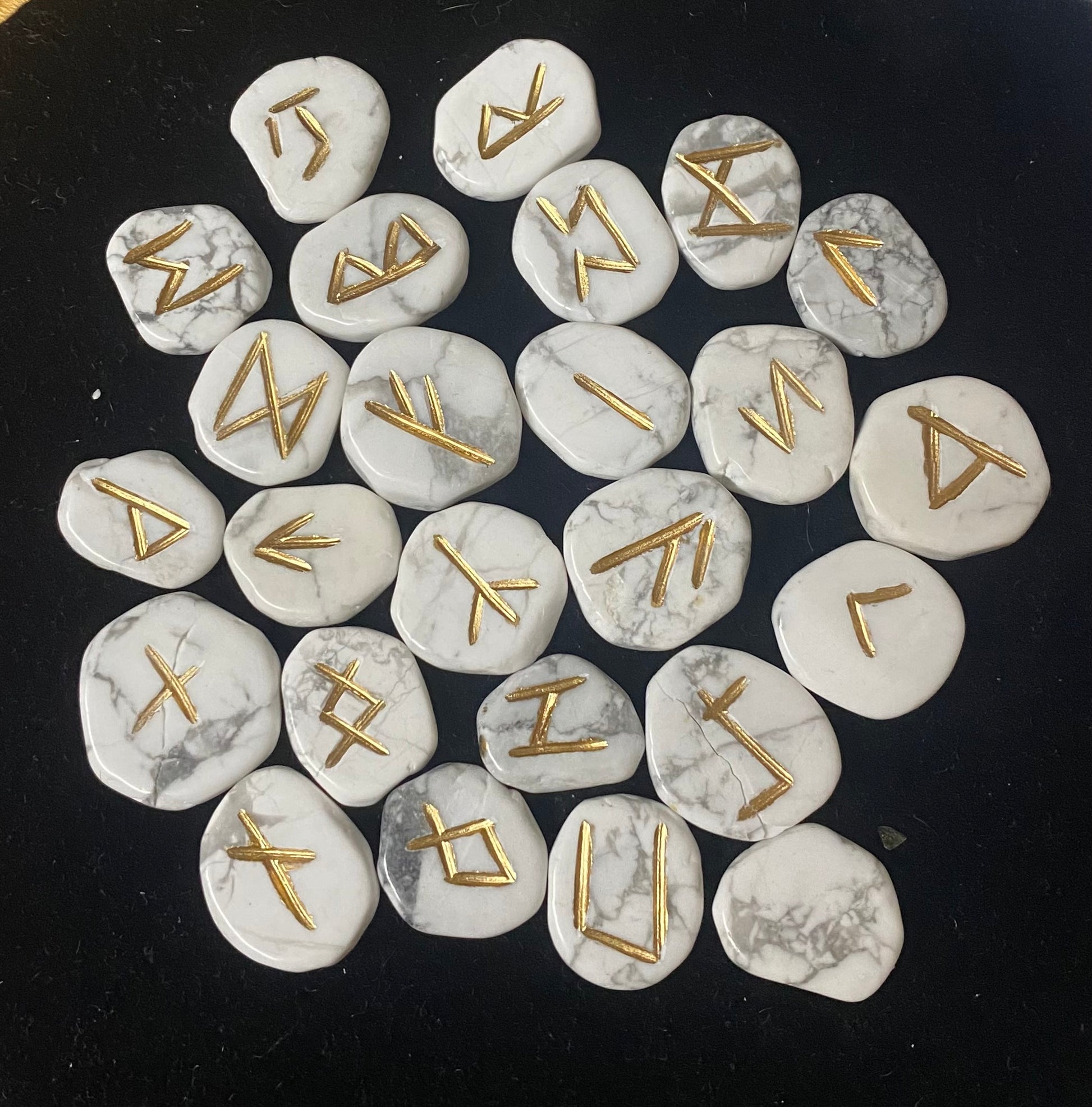 Rune Set Howlite stones with gold runes on a black background
