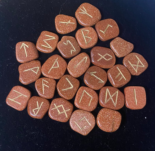 Rune Set Goldstone with engraved symbols on a black background