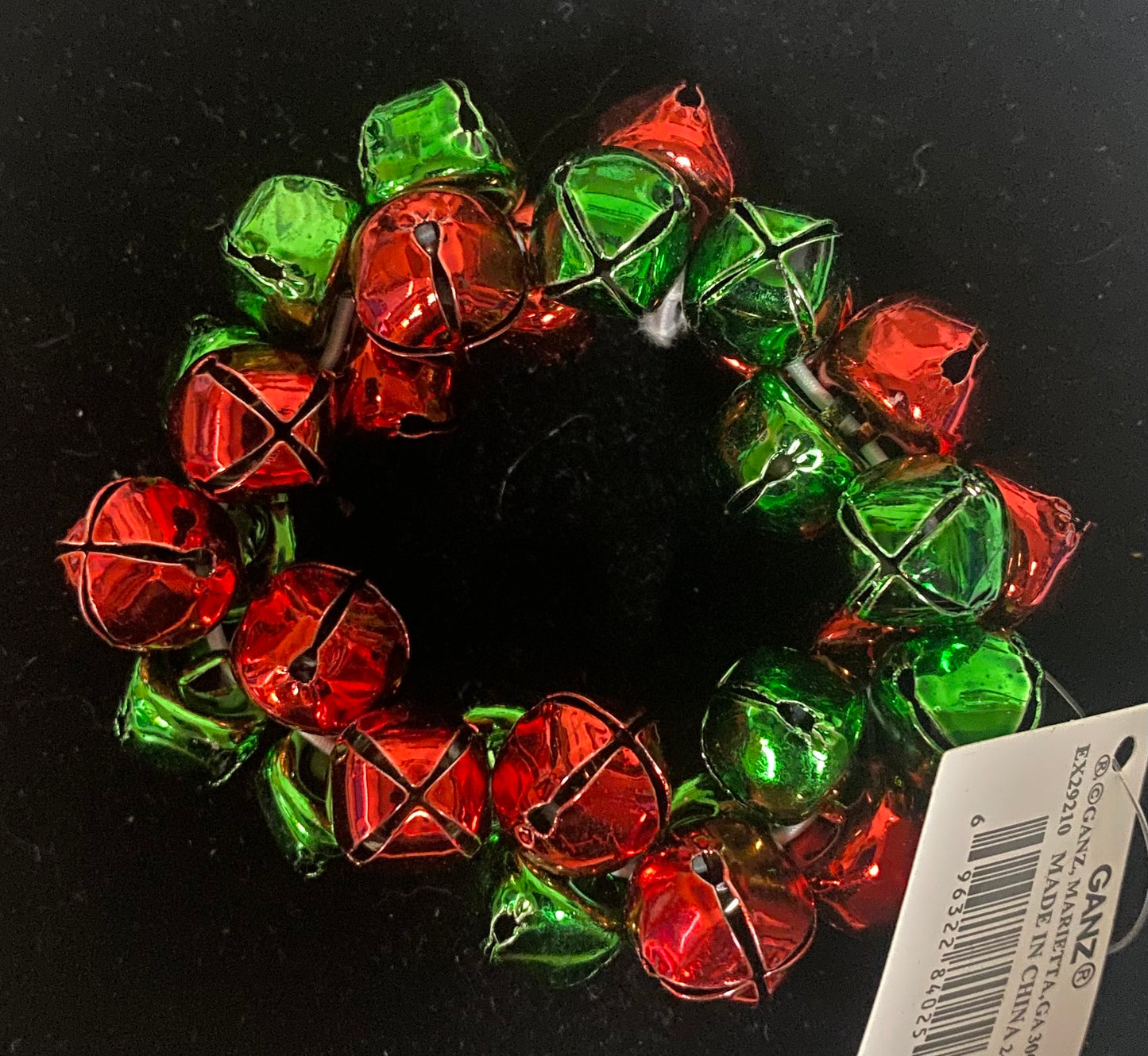 Decorative bracelet made of red and green bell-shaped ornaments on a black background.