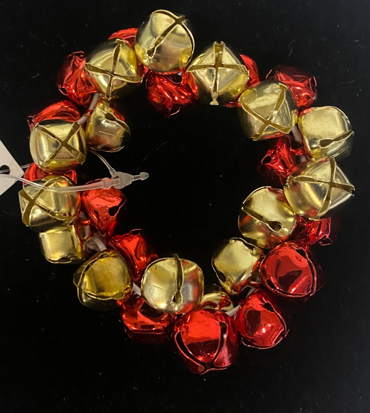 Decorative bracelet  made of red and gold bell-shaped objects on a black background