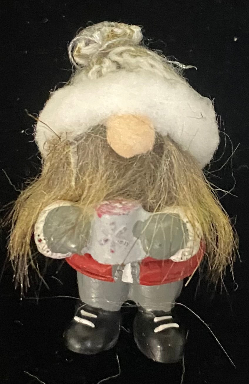 Decorative gnome charm with a red and white hat on a black background