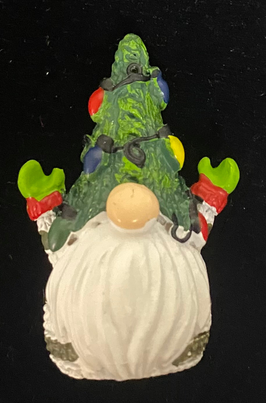 Decorative gnome with a green tree on its head against a black background