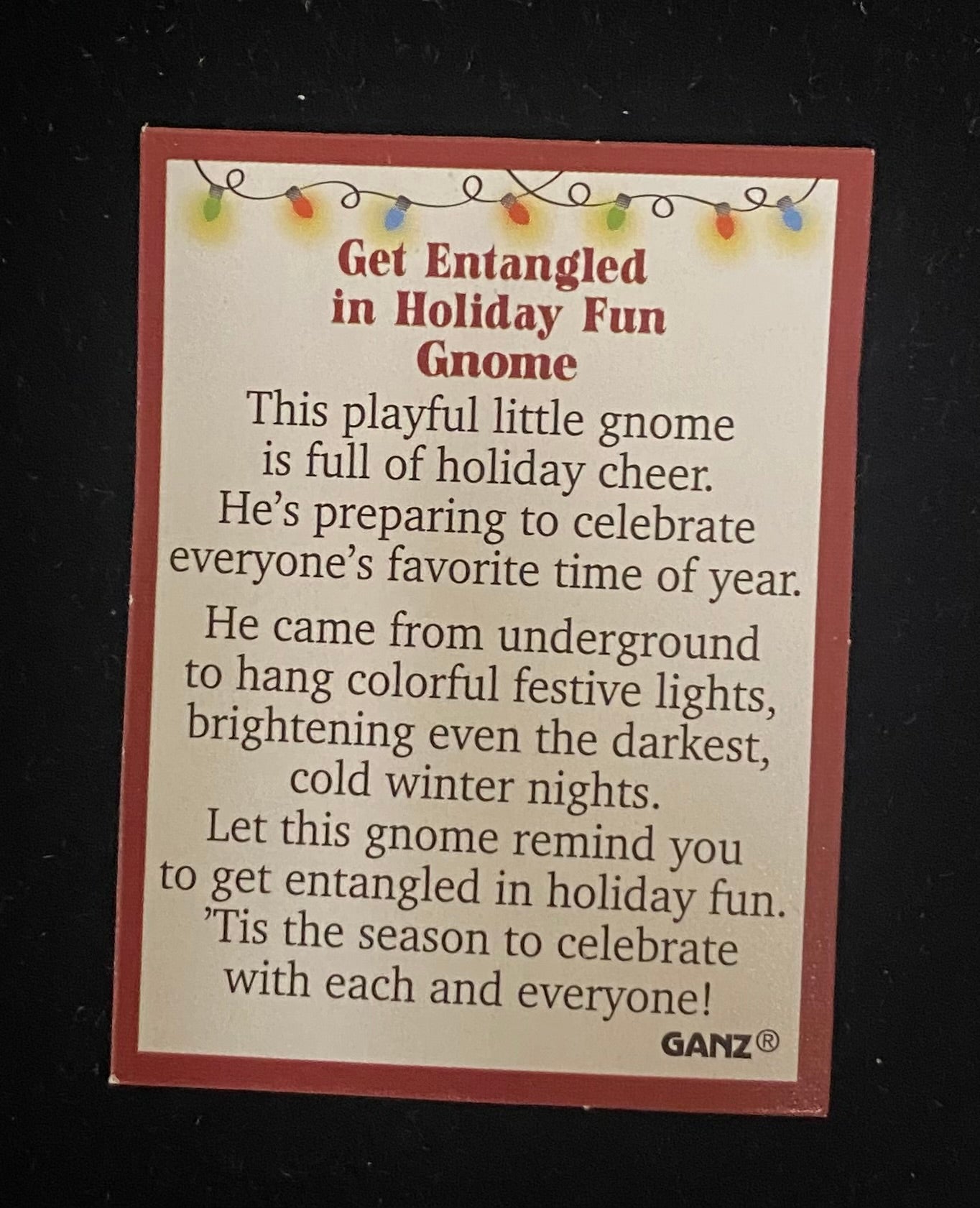 Product description card for a GANZ gnome with holiday lights on a black background