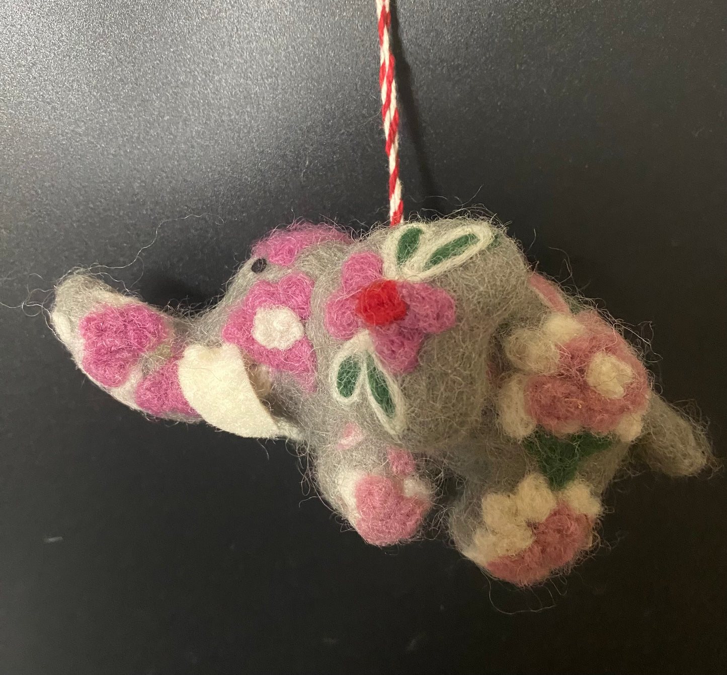 Handmade felted elephant ornament with floral patterns on a dark background