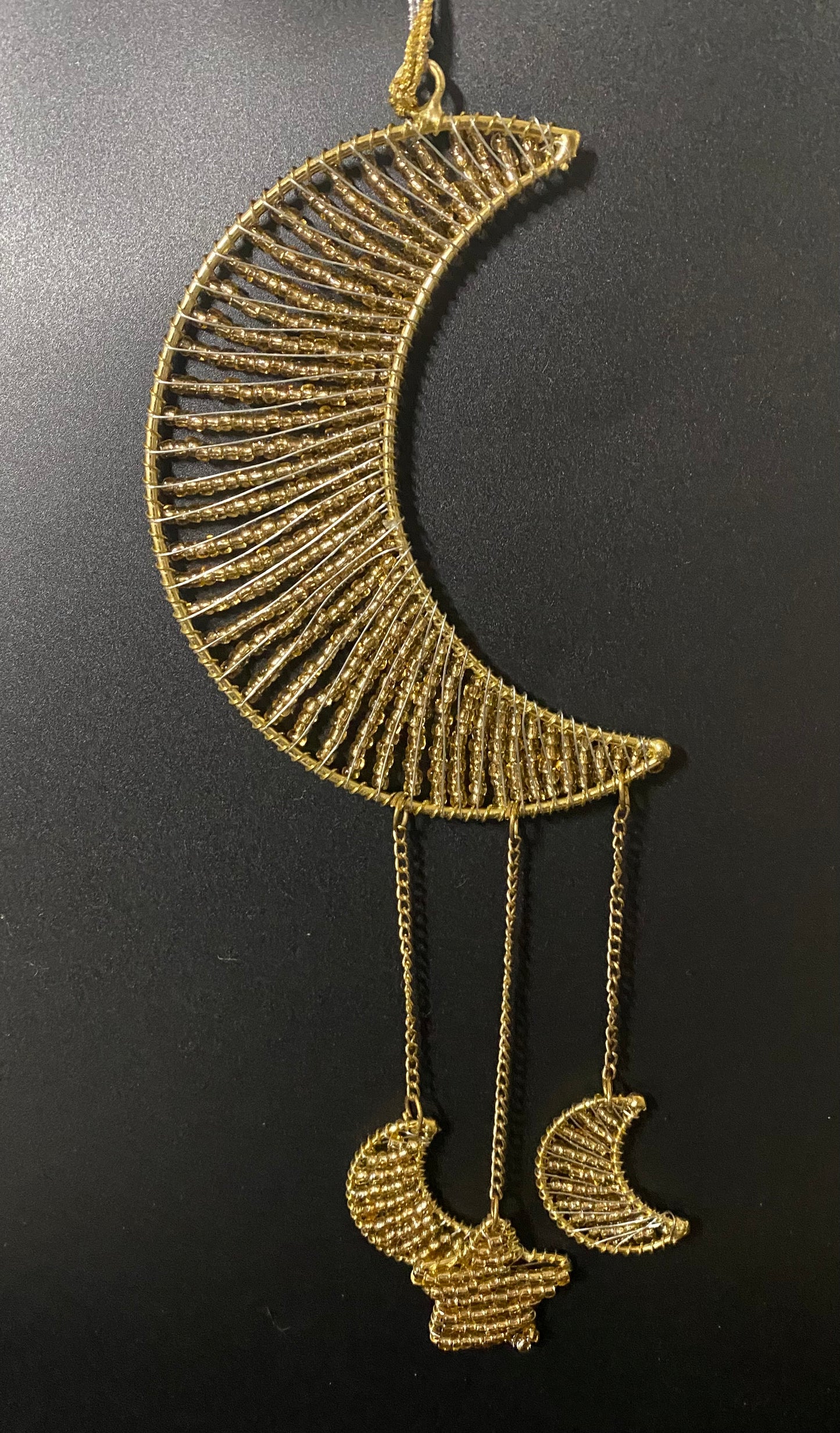 Decorative gold crescent moon with chain on a black background