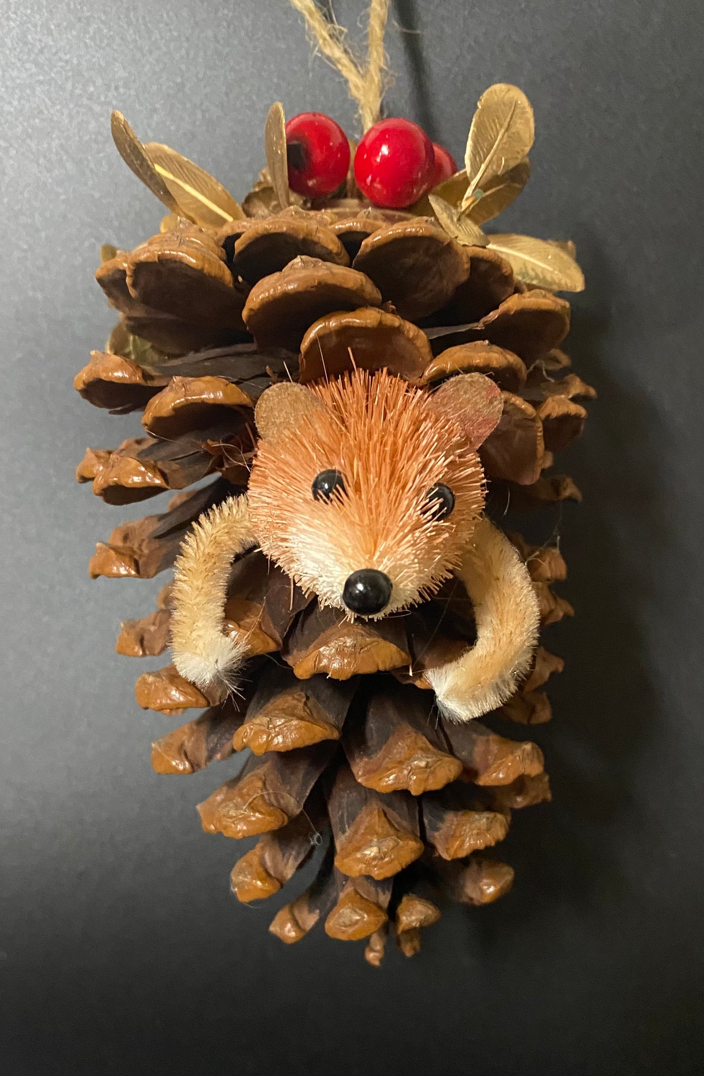 Decorative hedgehog ornament made from pine cones on a dark background