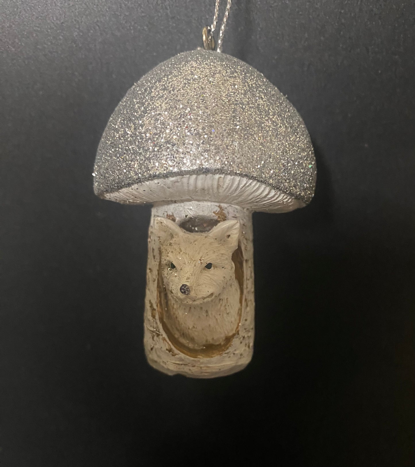 Decorative ornament shaped like a mushroom with a fox face inside, on a dark background.